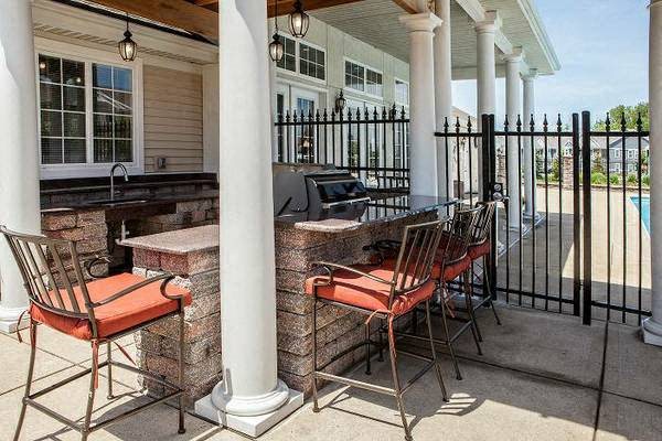 Patio grilling area with a bar and chairs and resident pool at Prairie Point Apartments