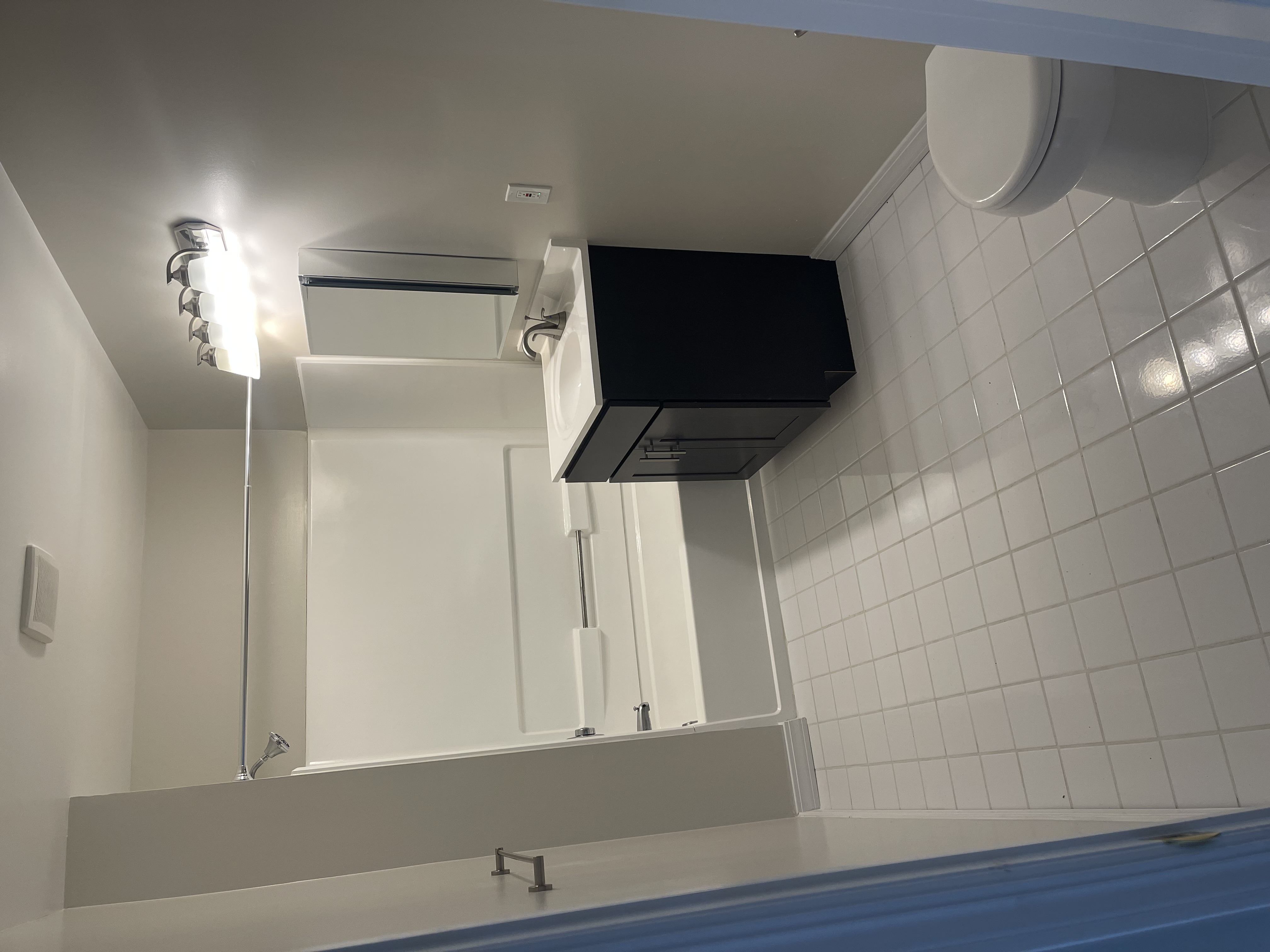 A bathroom with a white tiled wall and a white toilet.