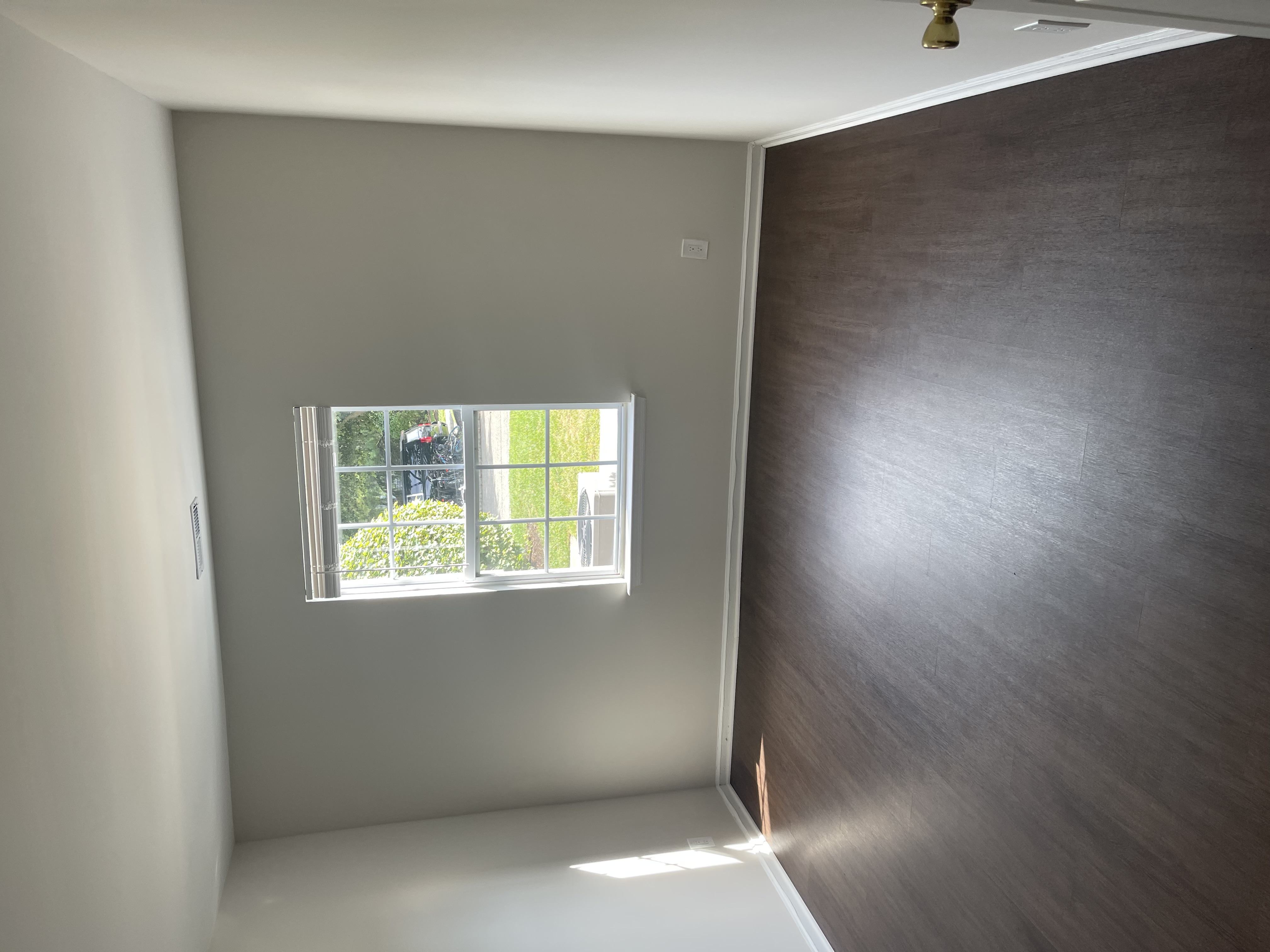 A room with a window and a brown wall.
