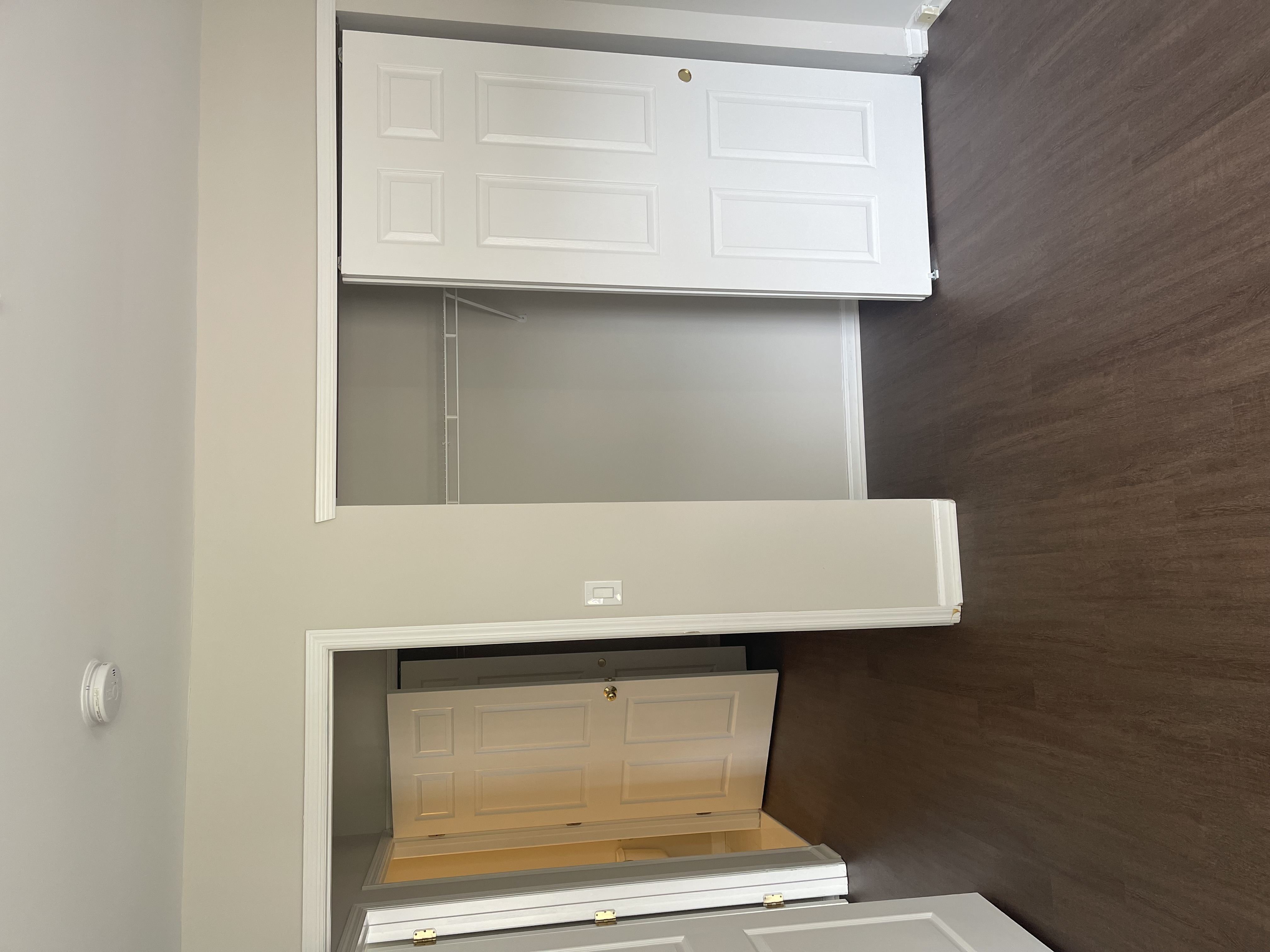 A white cabinet with a door open revealing a wooden drawer.