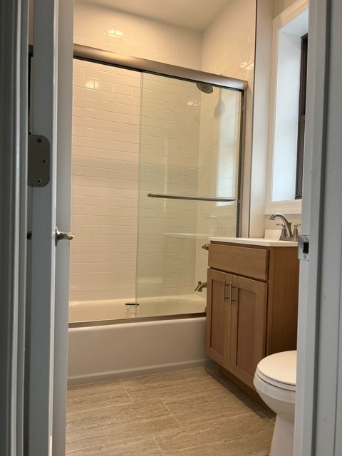 A bathroom with a toilet, a sink and a glass shower door.