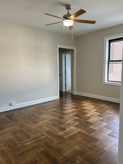 A room with a ceiling fan and wooden flooring.