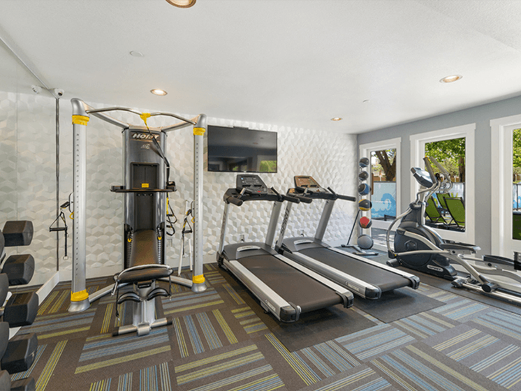 Apartments Federal Way - Bright Community Fitness Center with Multiple Machines and Large Windows that View the Pool