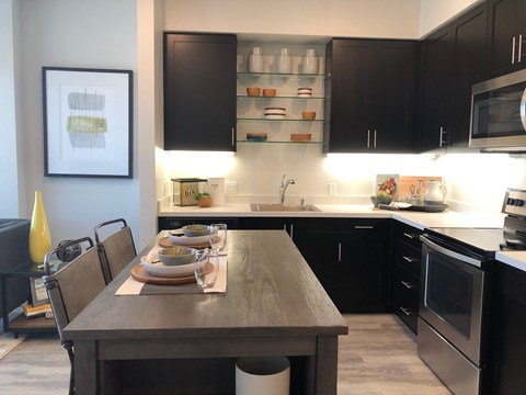 Luxury Apartments in Oakland CA - Rasa - Modern Kitchen with Stainless Steel Appliances, White Countertops, and Wood Flooring