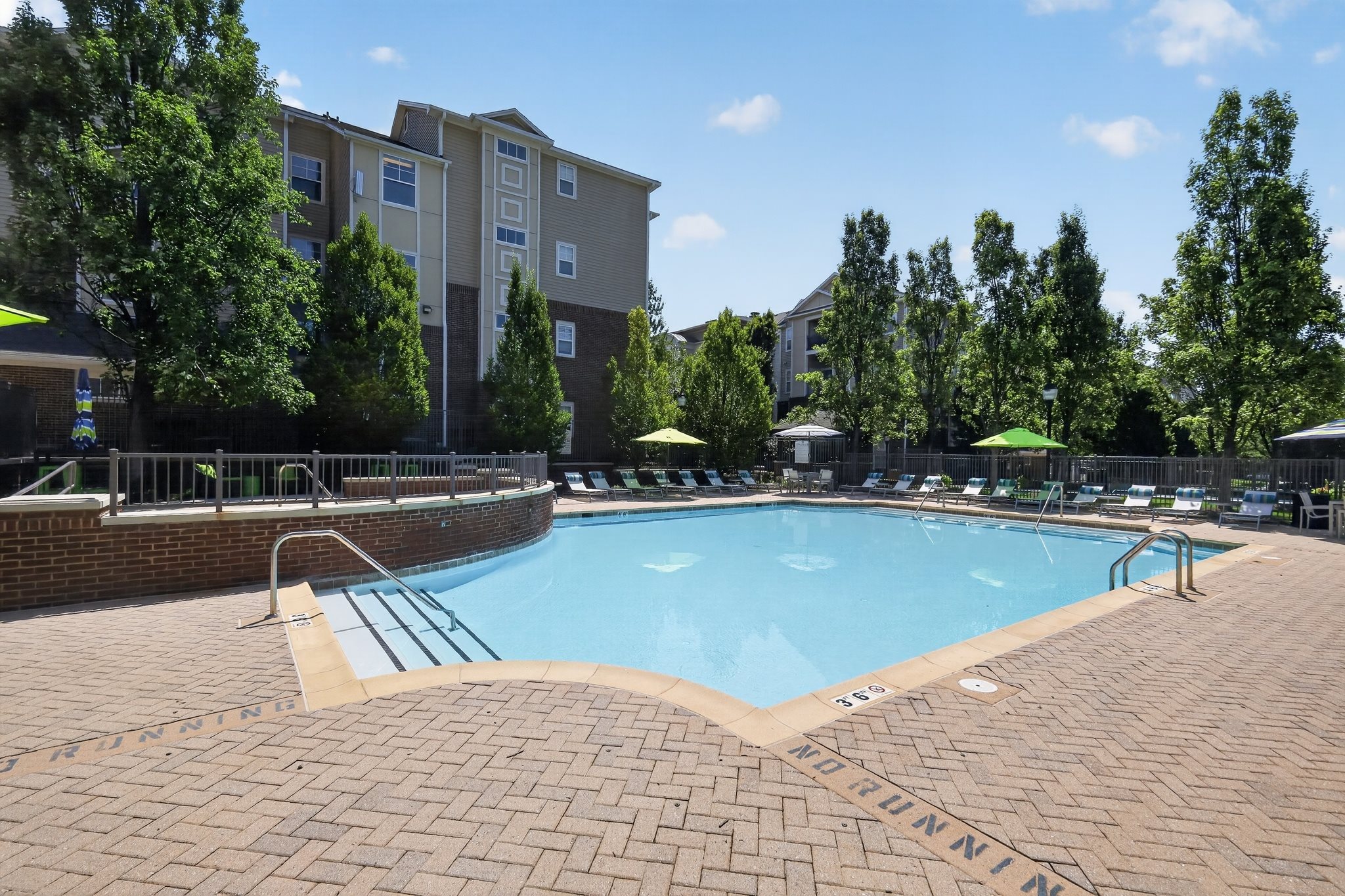 A pool surrounded by a brick patio with the word "PINNACLE" on it.