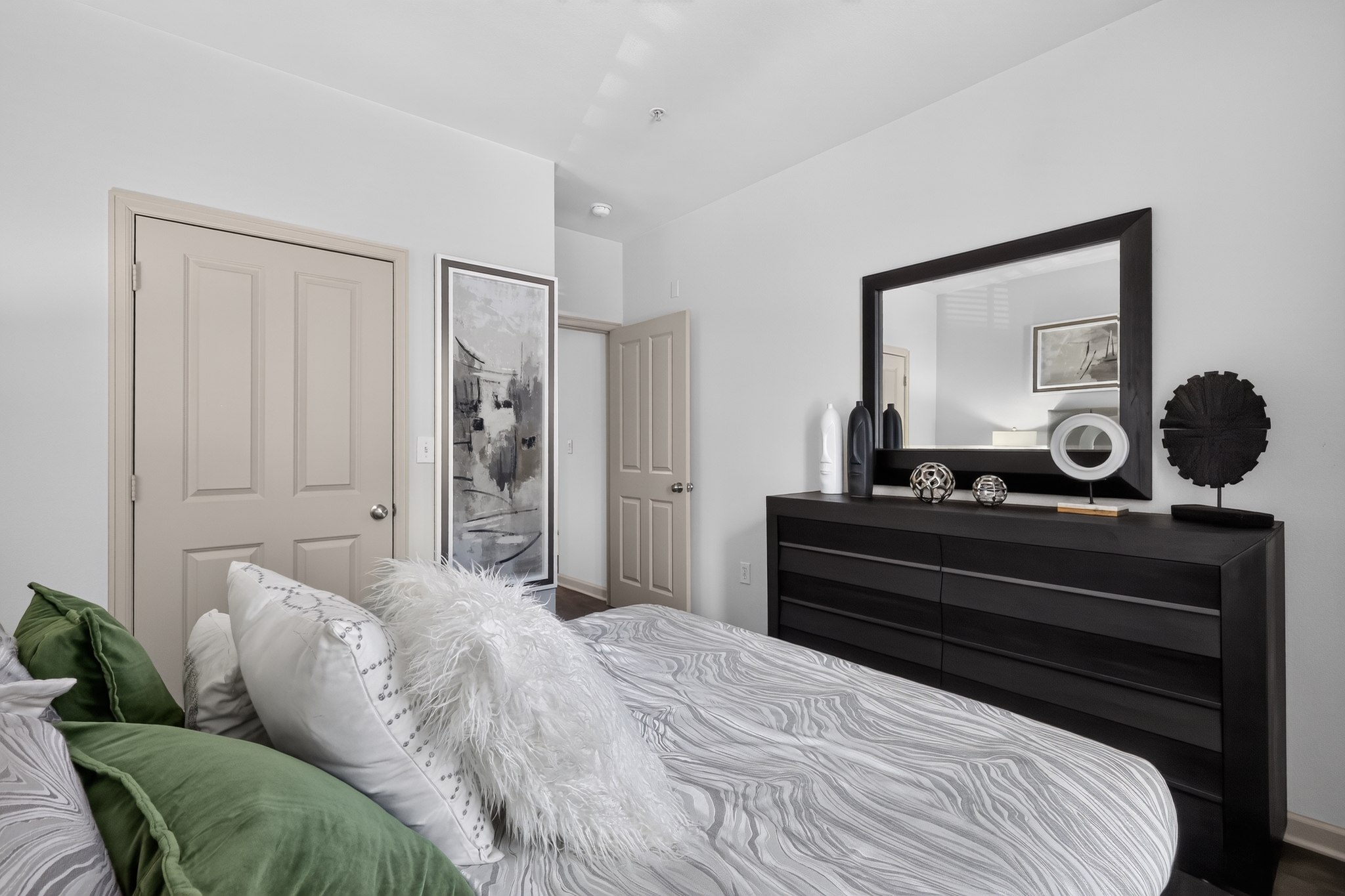 A bedroom with a bed, a dresser, and a mirror.
