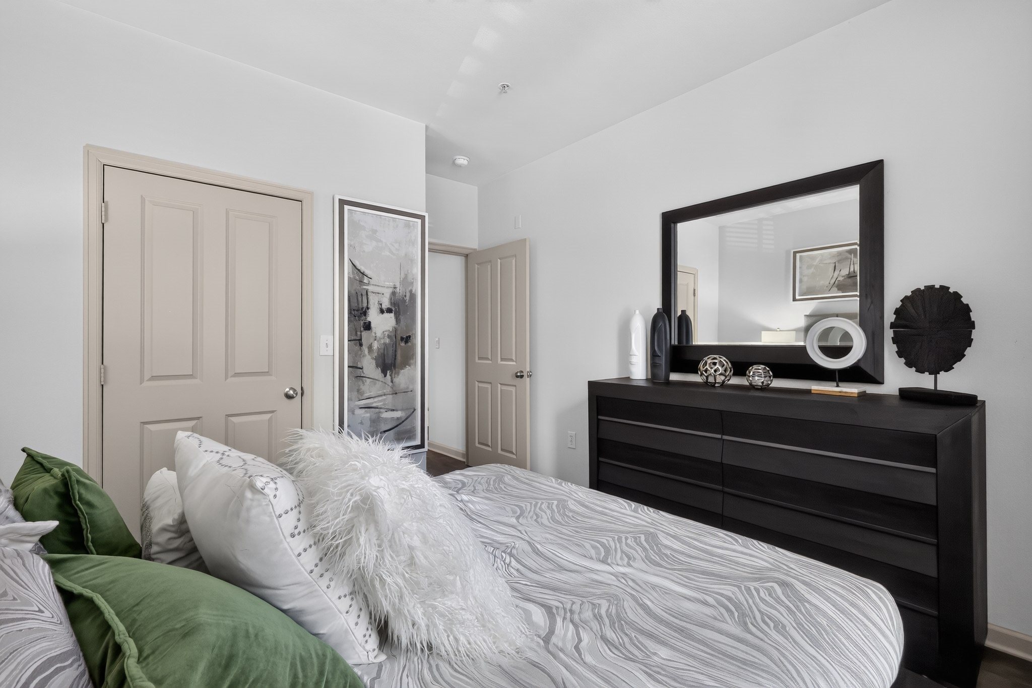 A bedroom with a bed, a dresser, and a mirror.