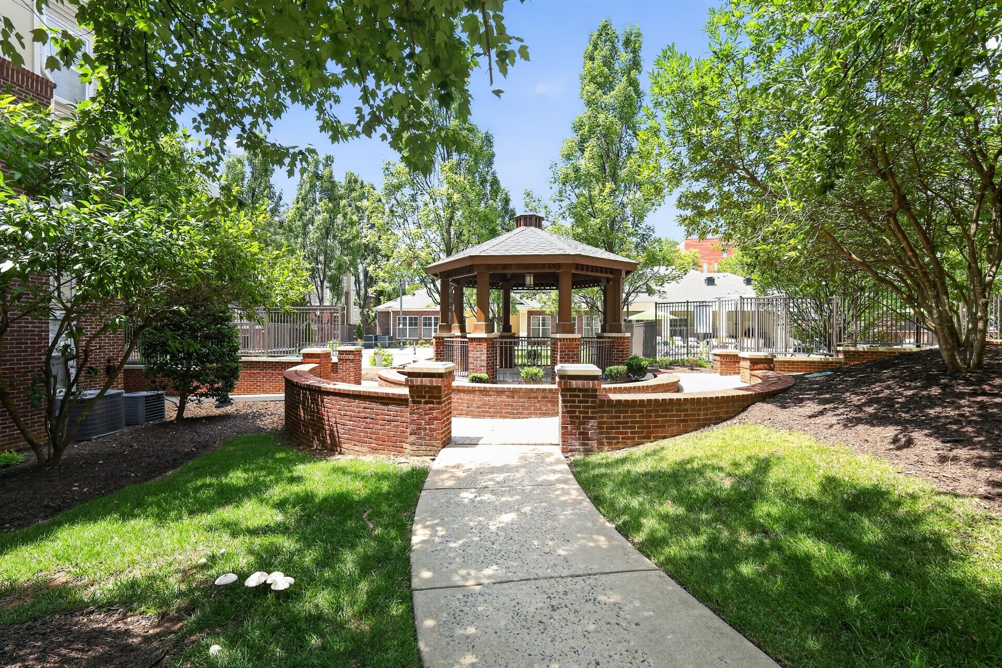 A gazebo is surrounded by a brick wall and a concrete walkway.