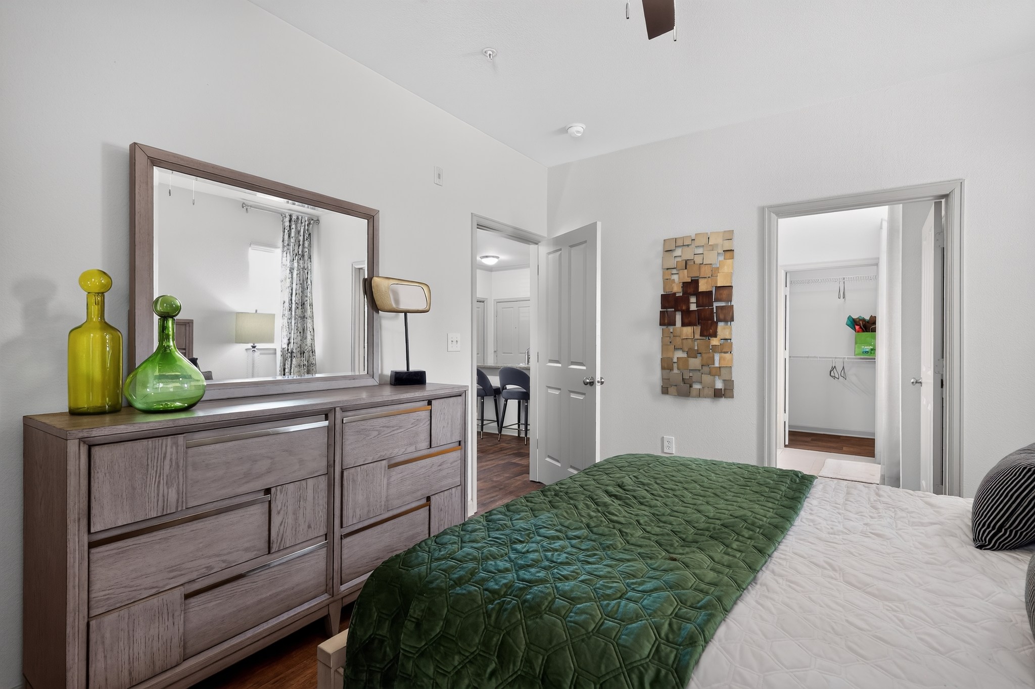 A bedroom with a large bed and a dresser with a mirror above it.