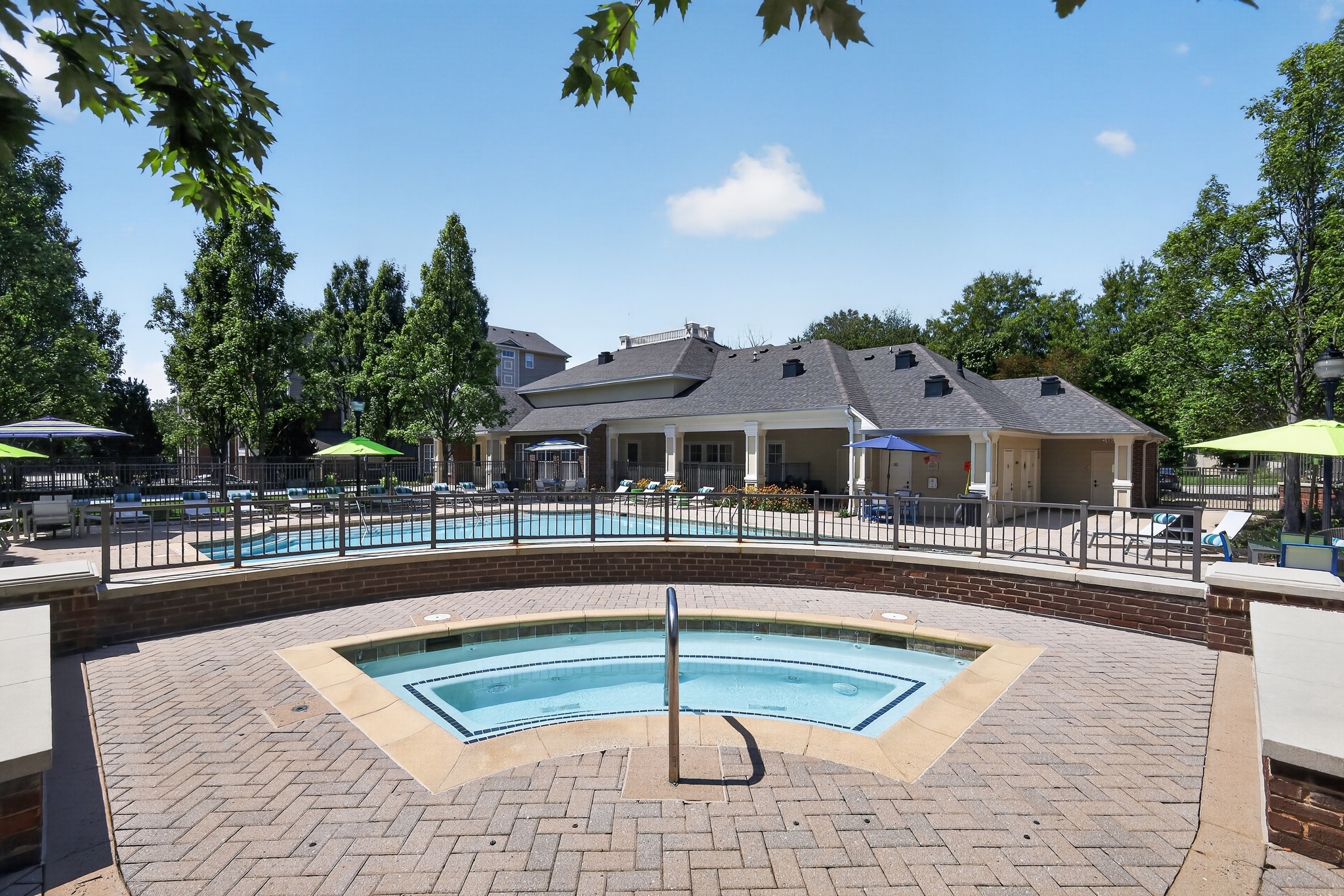 A pool surrounded by a brick patio with a house in the background.