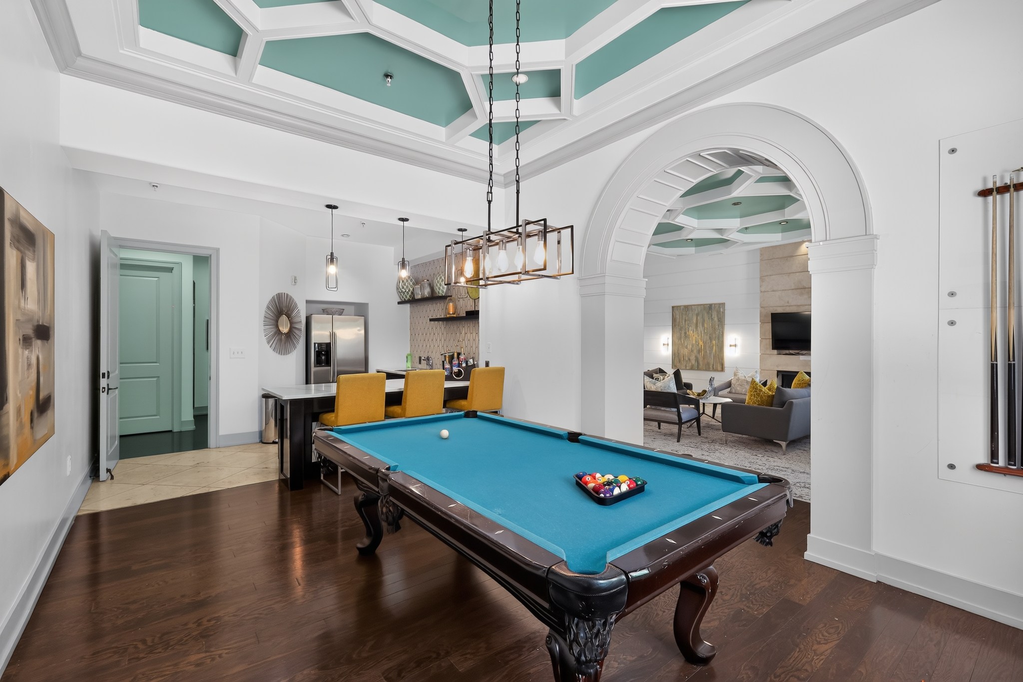 A pool table is in the middle of a room with a green door.