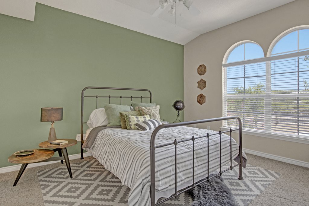 Luxury Three-Bedroom Apartments in San Antonio, TX - Spacious Bedroom with Arch Windows, Plush Carpet, and Ceiling Fan