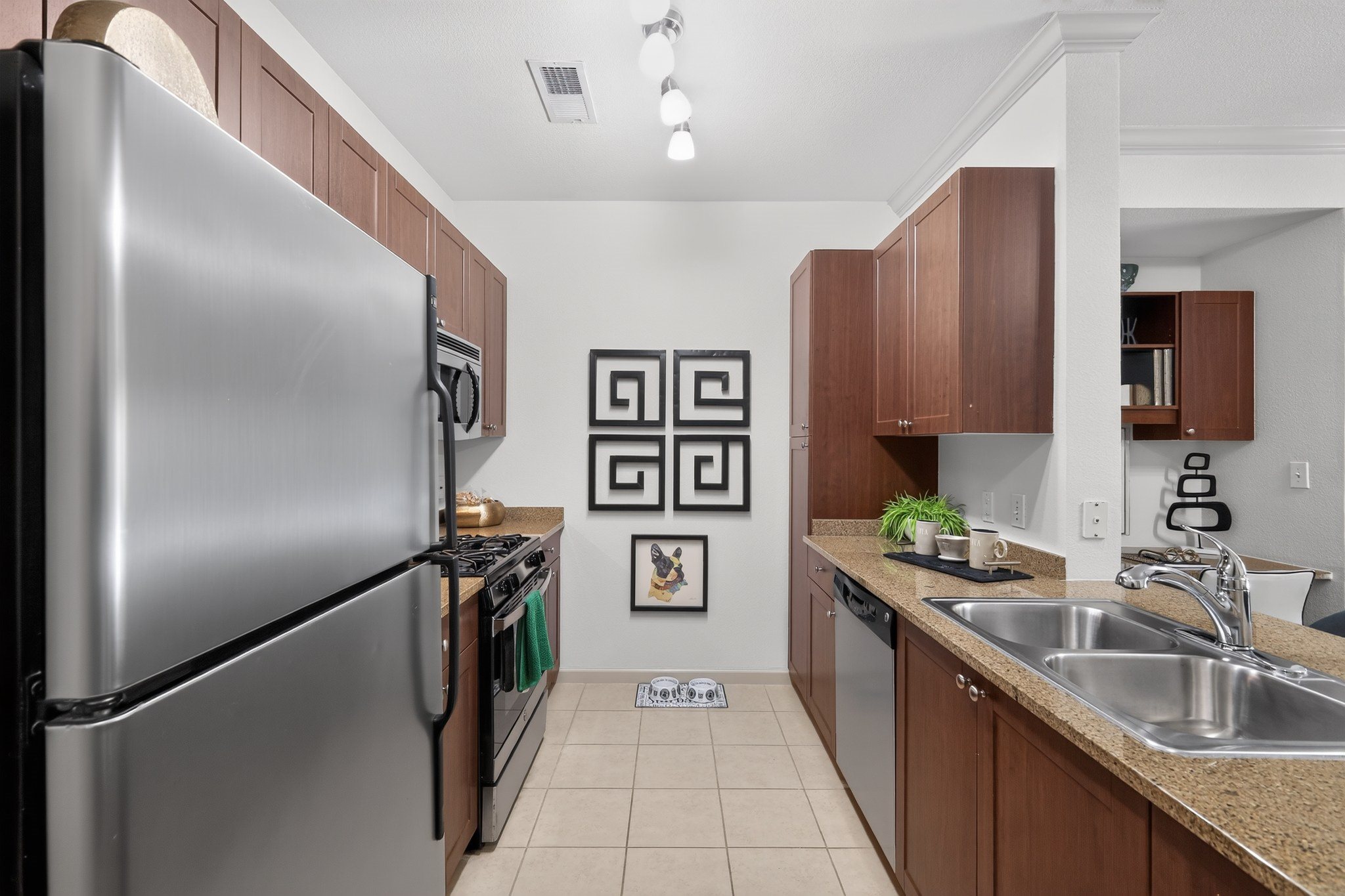 A kitchen with a refrigerator, sink, and cabinets.