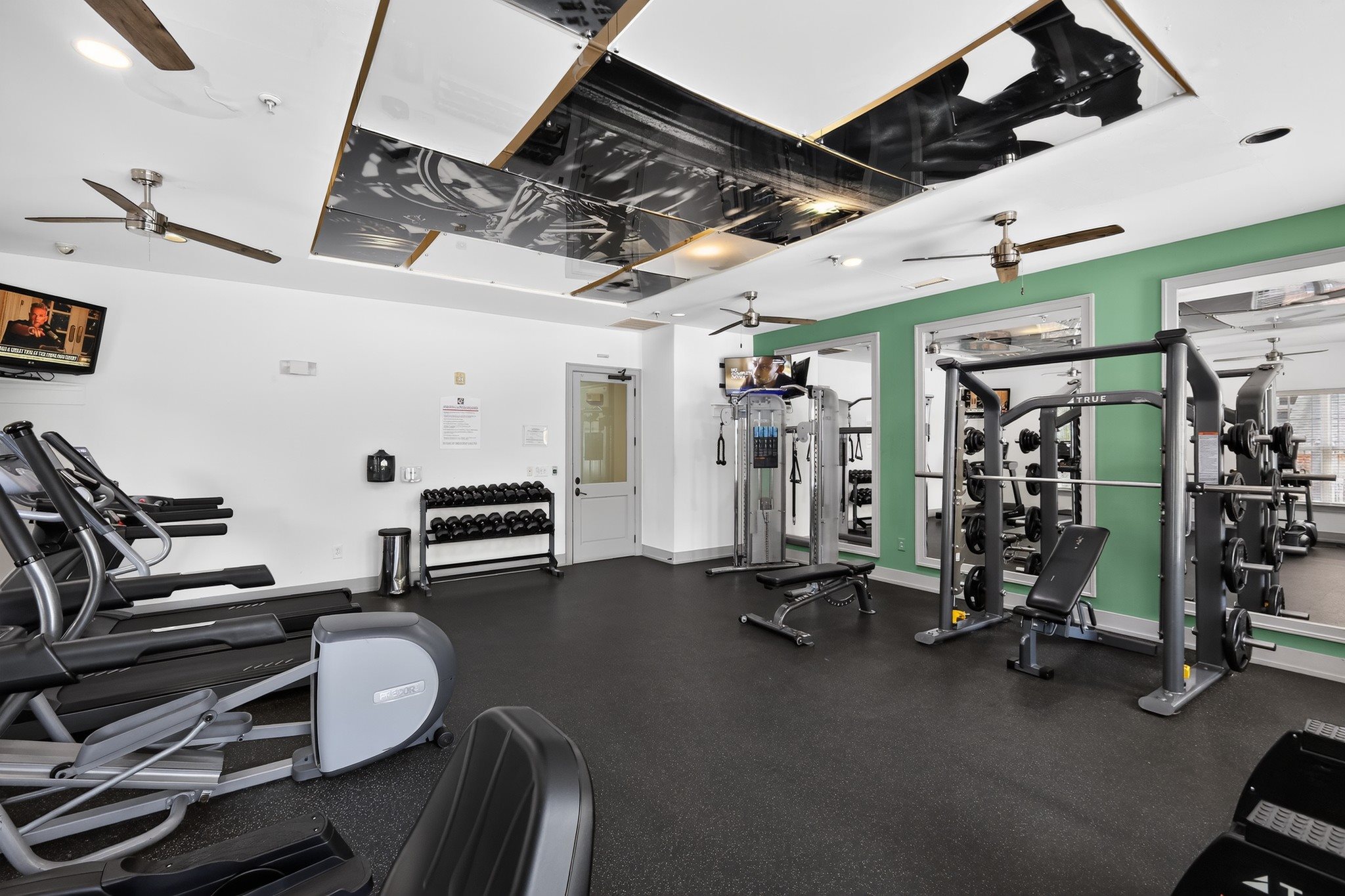 A gym with treadmills, weights, and exercise equipment.