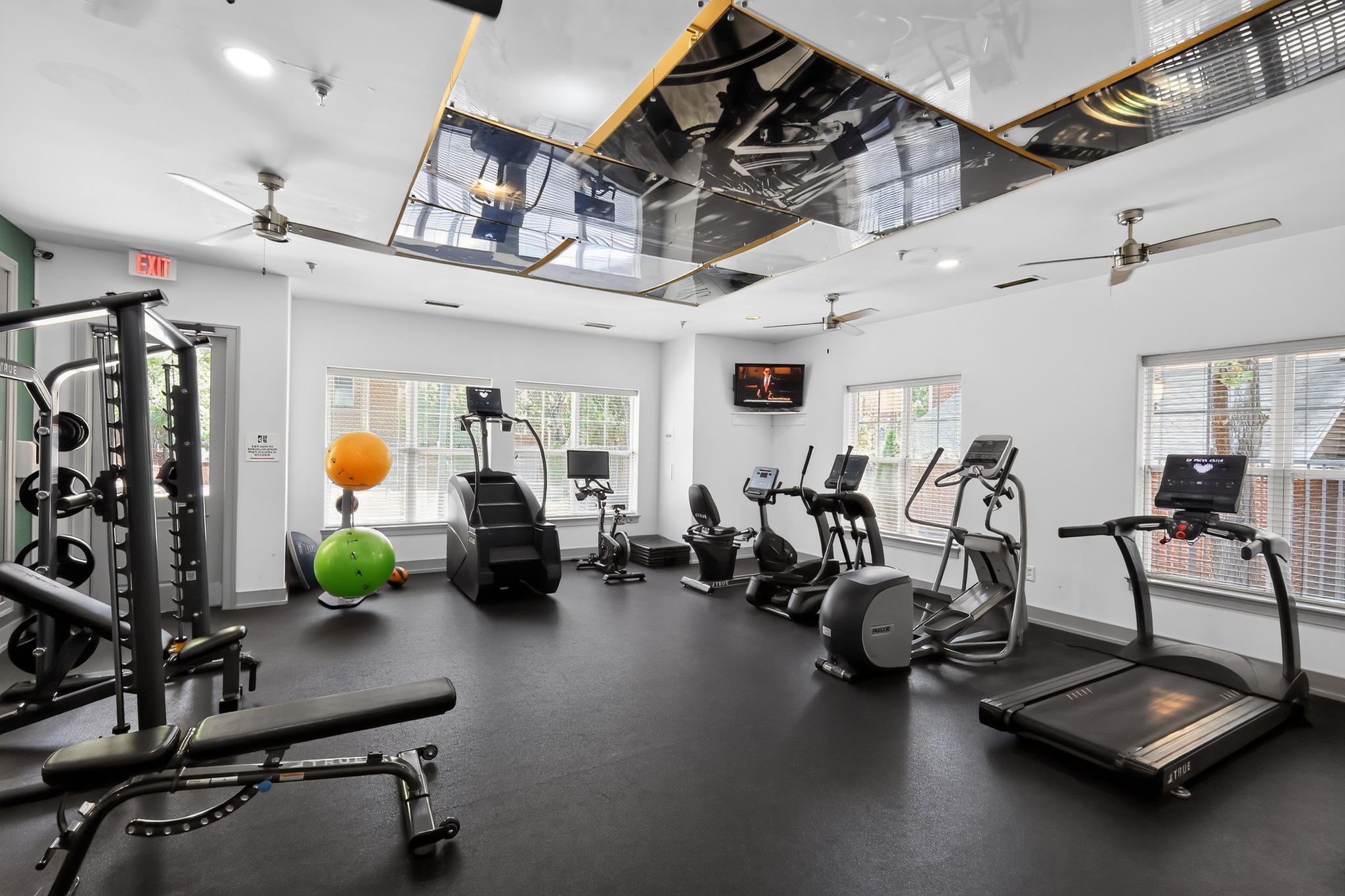 A gym with a variety of exercise equipment including treadmills, stationary bikes, and weight machines.
