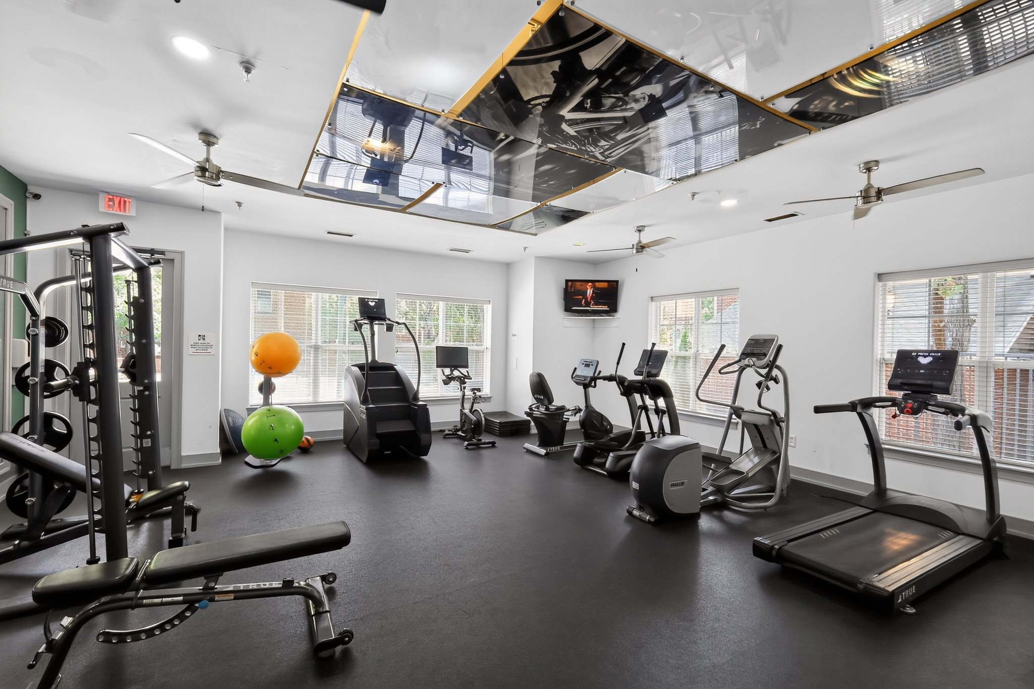 A gym with a variety of exercise equipment including treadmills, stationary bikes, and weight machines.