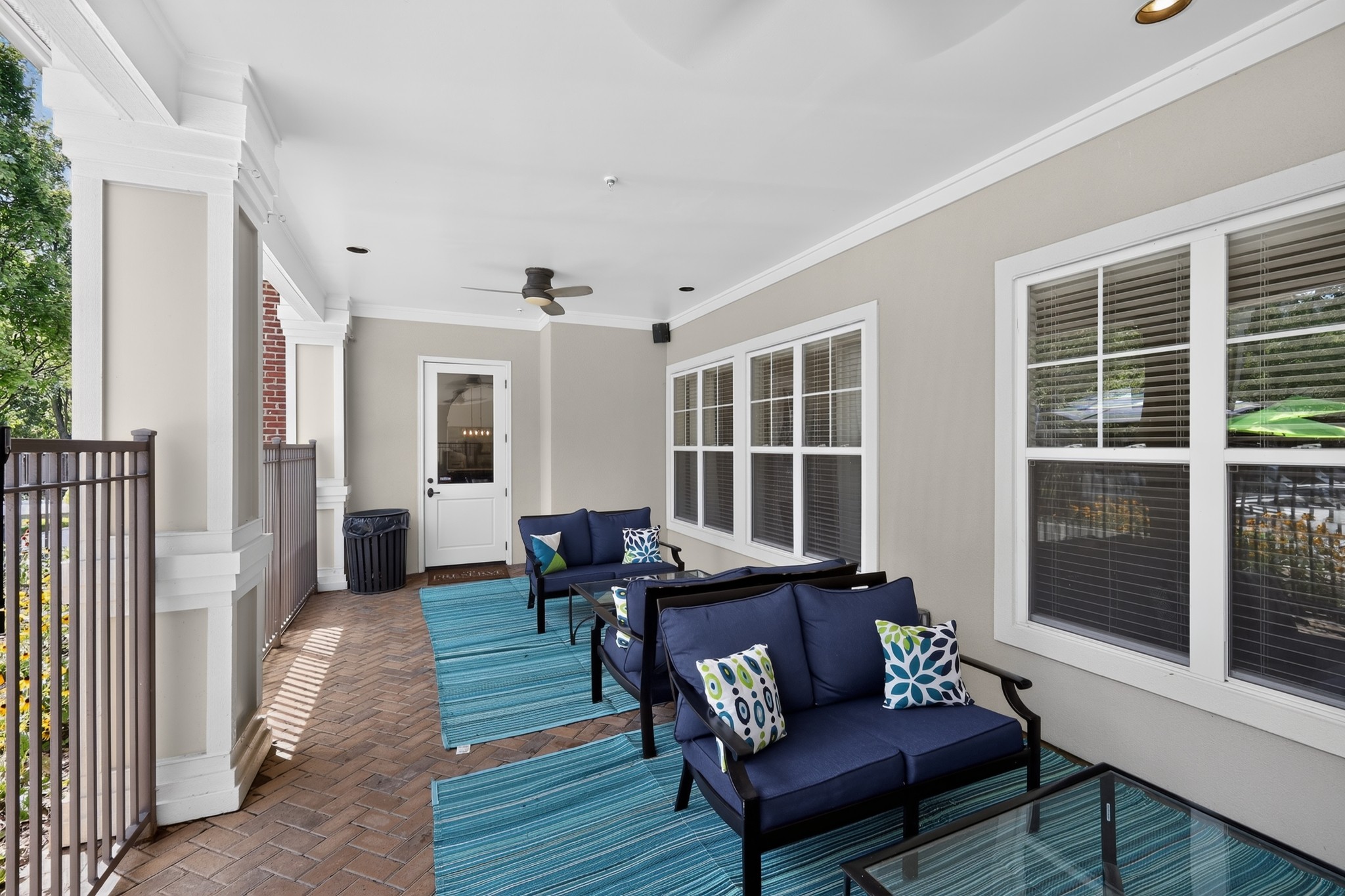 A patio with a blue couch and a fan.