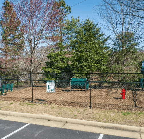 Fenced dog park with benches, tunnel, and fire hydrant.