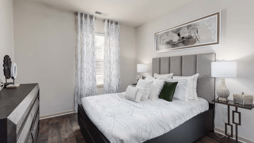 Modern bedroom with gray headboard, white bedding, and neutral decor.