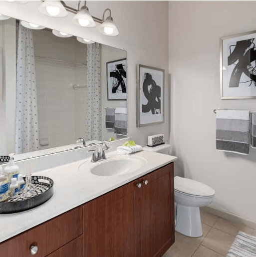 Modern bathroom with wood vanity, white countertop, and abstract art.