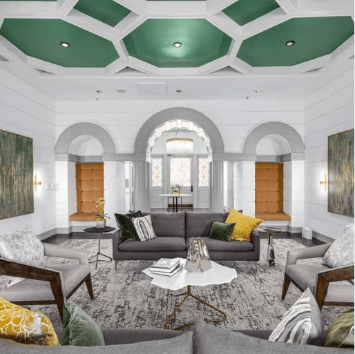 Elegant living room with gray sofas, armchairs, and a green geometric ceiling.