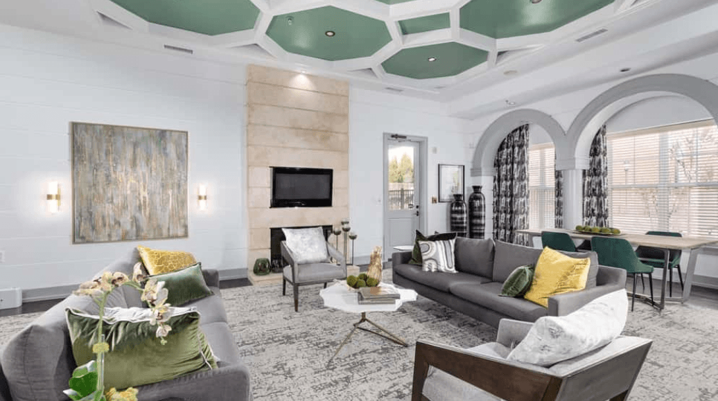 Modern living room with gray sofas, fireplace, and green ceiling accents.