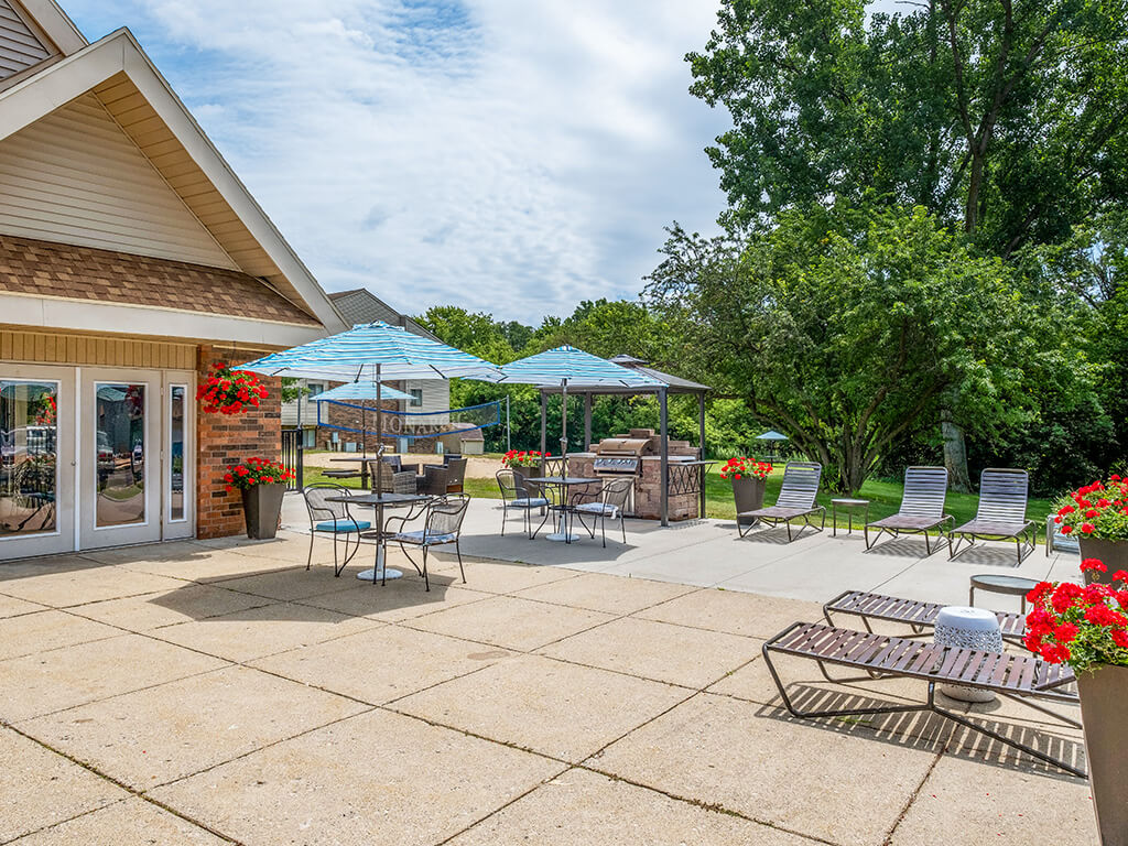 Sun deck patio with tables and chairs under umbrellas at apartment complex