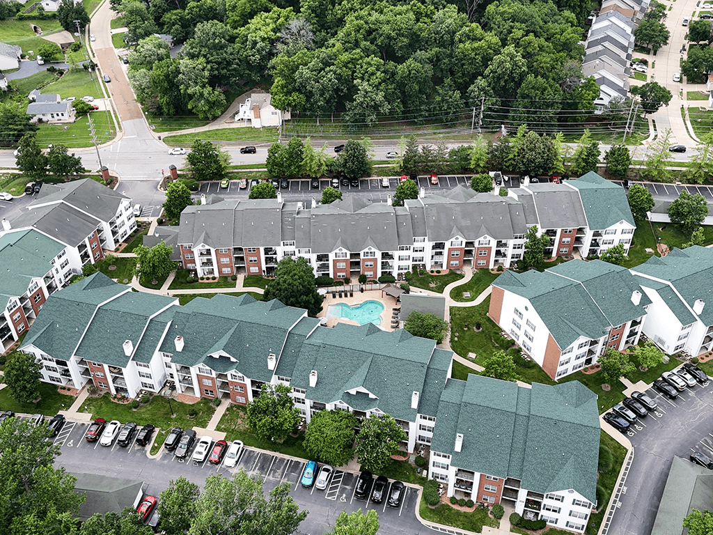 An aerial view of apartment buildings with a pool in the middle.