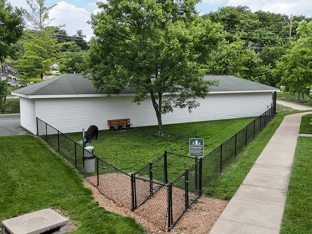 A white building with a black fenced dog park  in front of it.