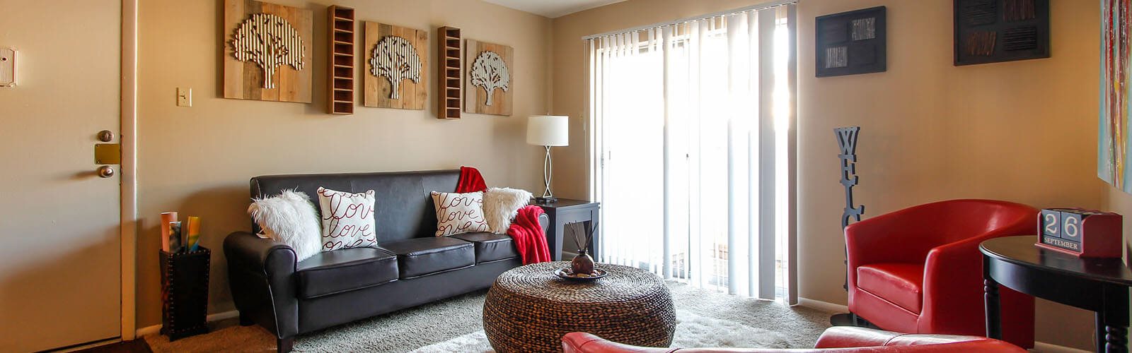 A living room with a black couch and a red chair.