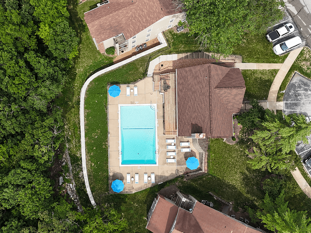 An aerial view of a house with a pool and a car parked in the driveway.