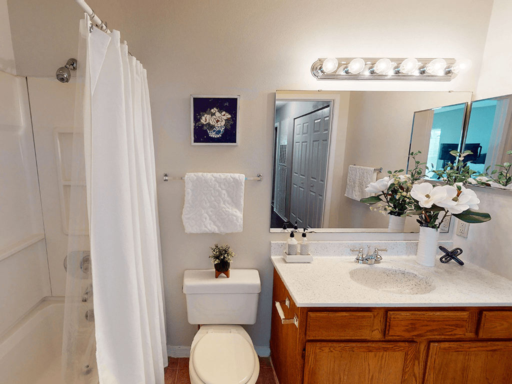 A white bathroom with a toilet, sink, and shower.