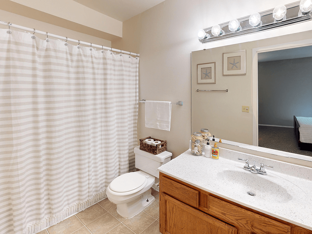 A bathroom with a toilet, sink, and shower curtain.