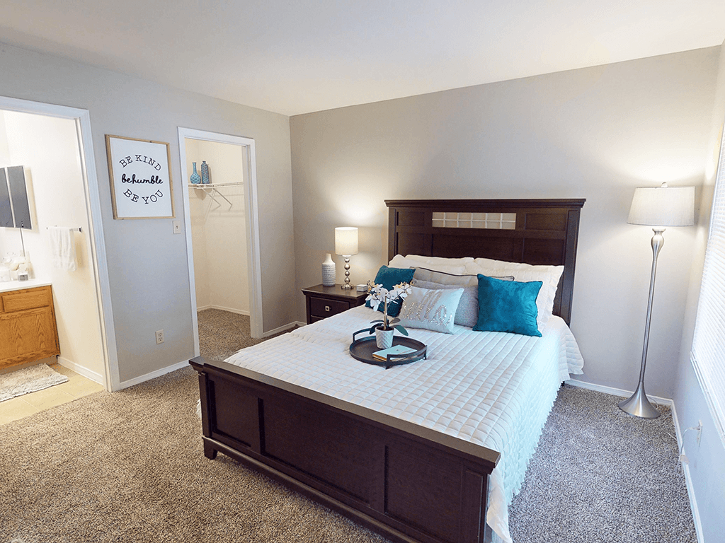 A bedroom with a large bed and a carpeted floor.
