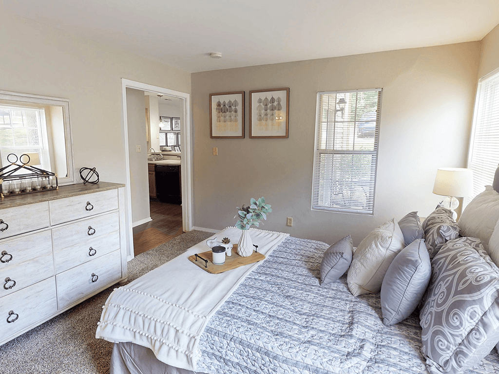 A bedroom with a large bed and a dresser with heart-shaped handles.