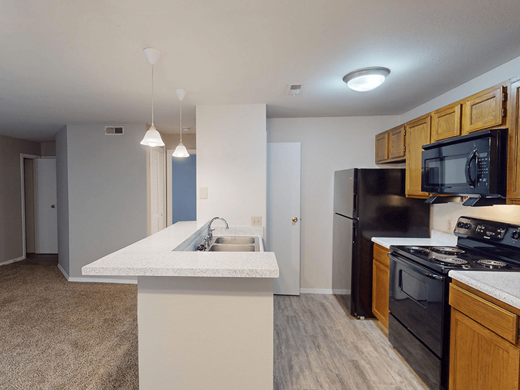 A kitchen with black appliances and wooden cabinets.