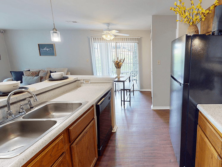 A kitchen with a black fridge and wooden cabinets.