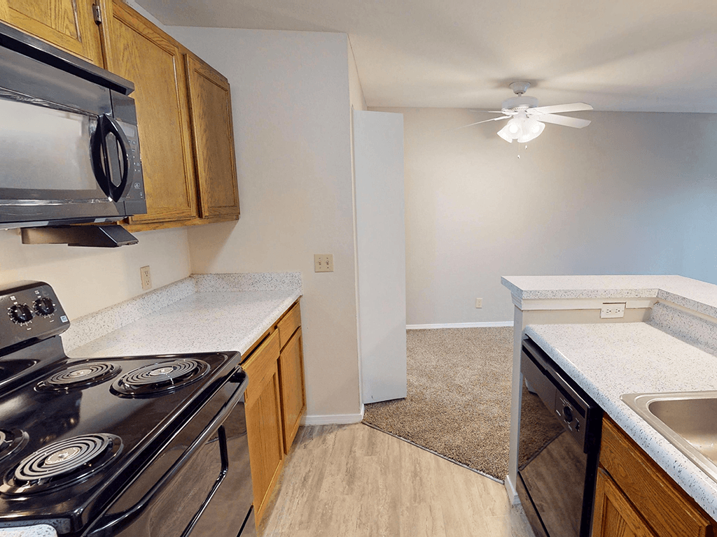 A kitchen with a stove, sink, and cabinets.