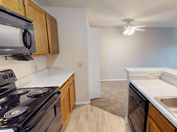 A kitchen with a stove, sink, and cabinets.