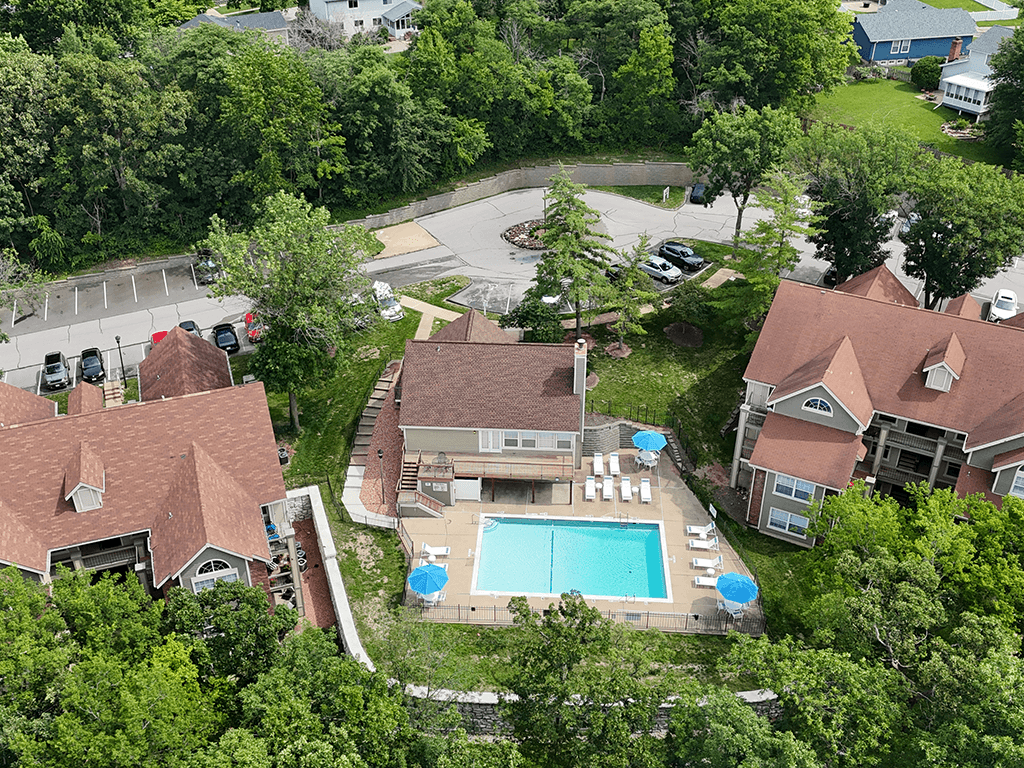 A bird's eye view of a house with a pool surrounded by trees.