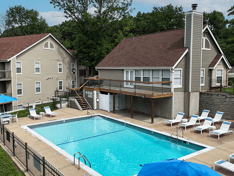 A swimming pool in a backyard with a deck and chairs.