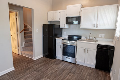 Spacious kitchen with white cabinetry, black energy efficient appliances and plank style flooring
