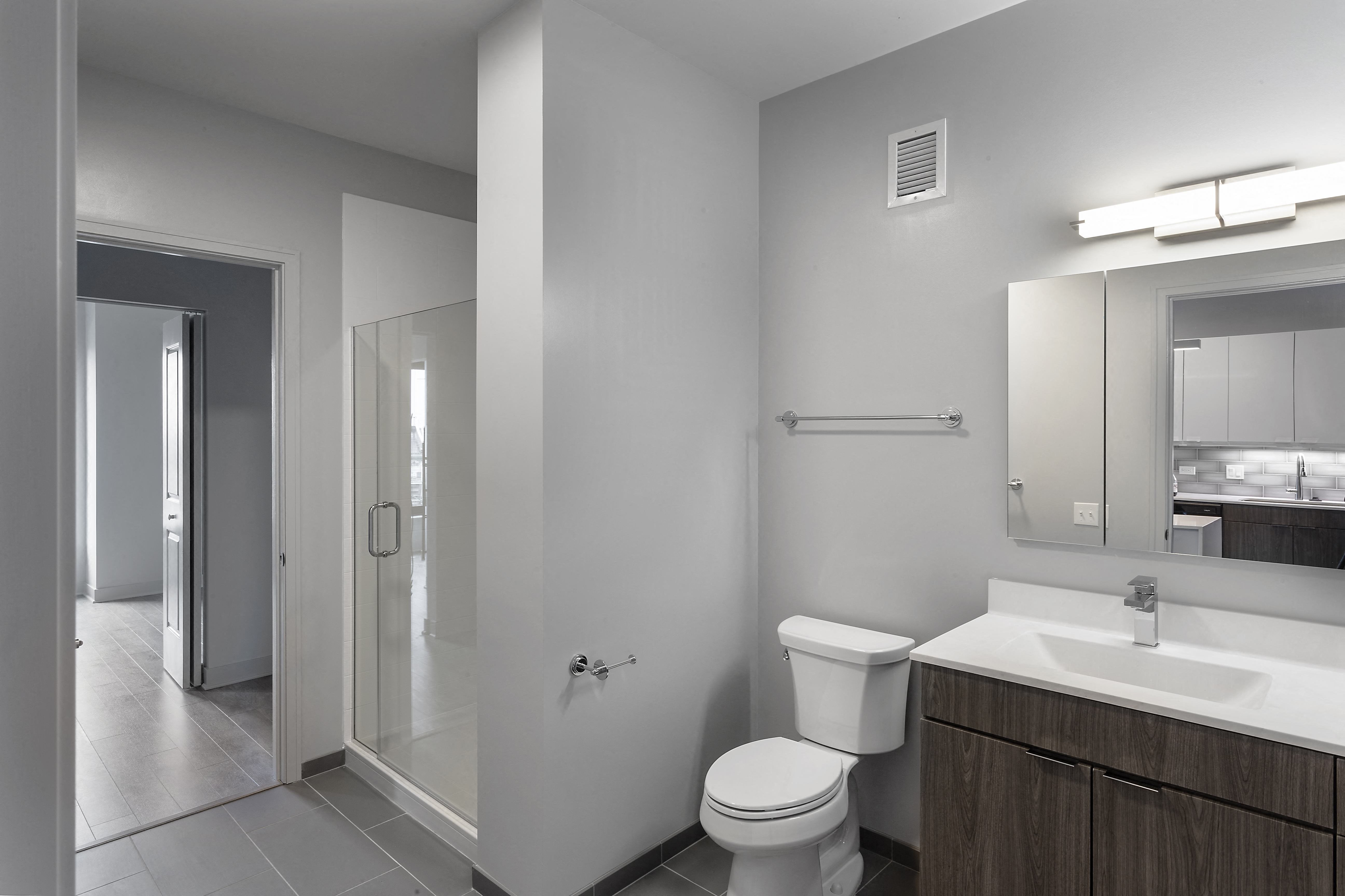 a bathroom with a toilet sink and mirror and a shower at Residences at Addison Clark Apartments, IL, 60613