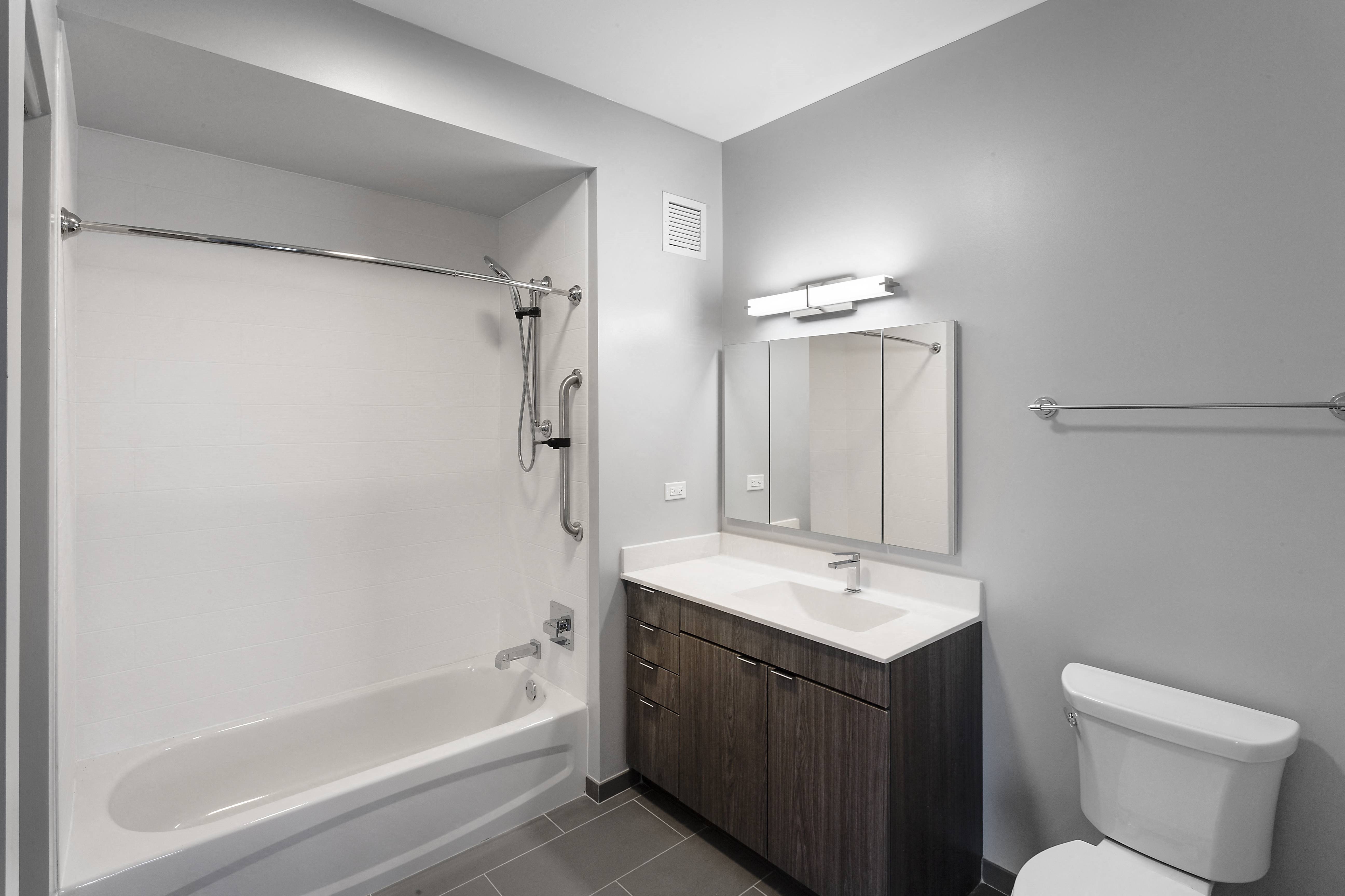 a bathroom with a toilet sink and shower and a mirror at Residences at Addison Clark Apartments, Chicago, IL