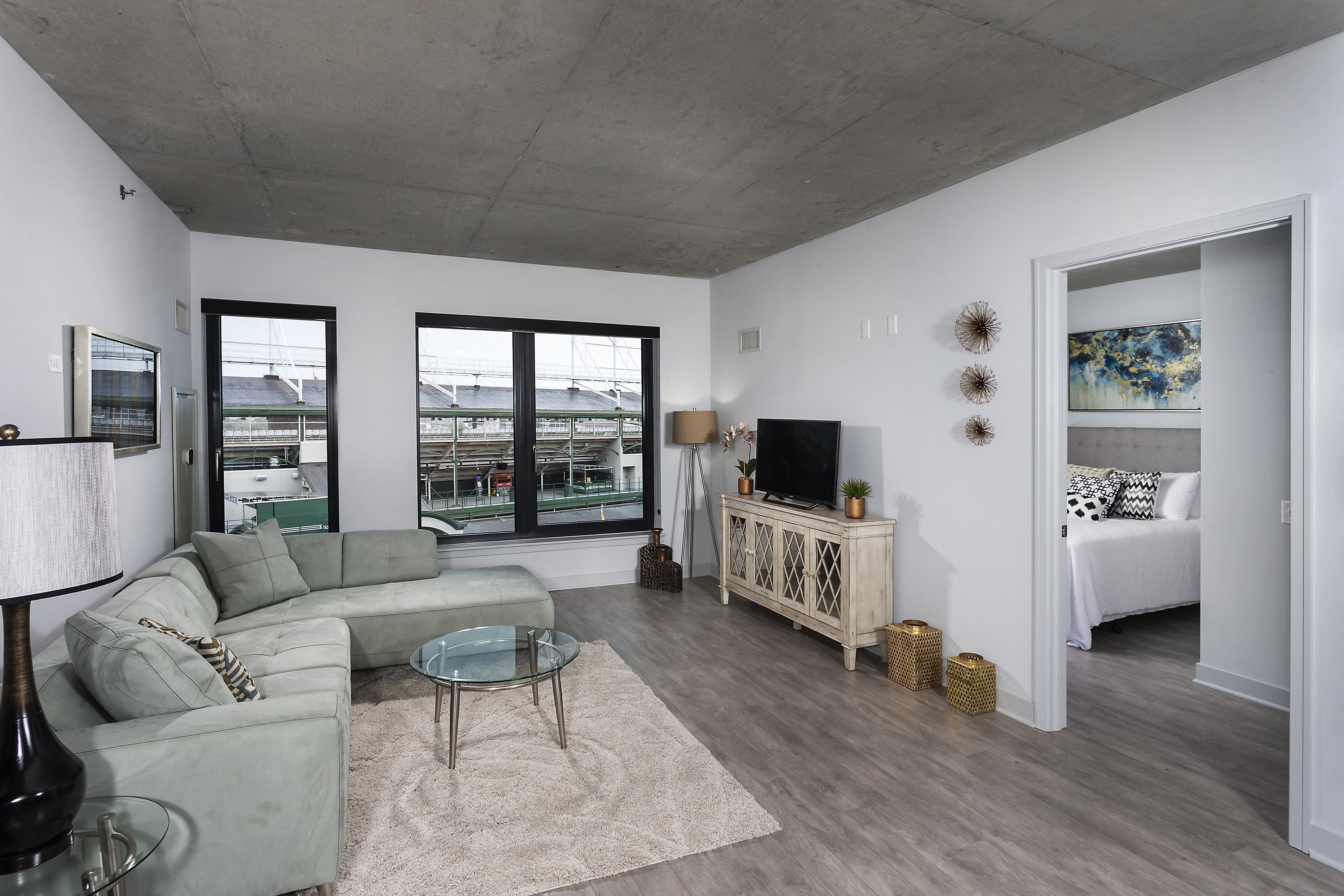 a living room with a gray couch and a glass coffee table and sliding glass doors at Residences at Addison Clark Apartments, Chicago, IL, 60613
