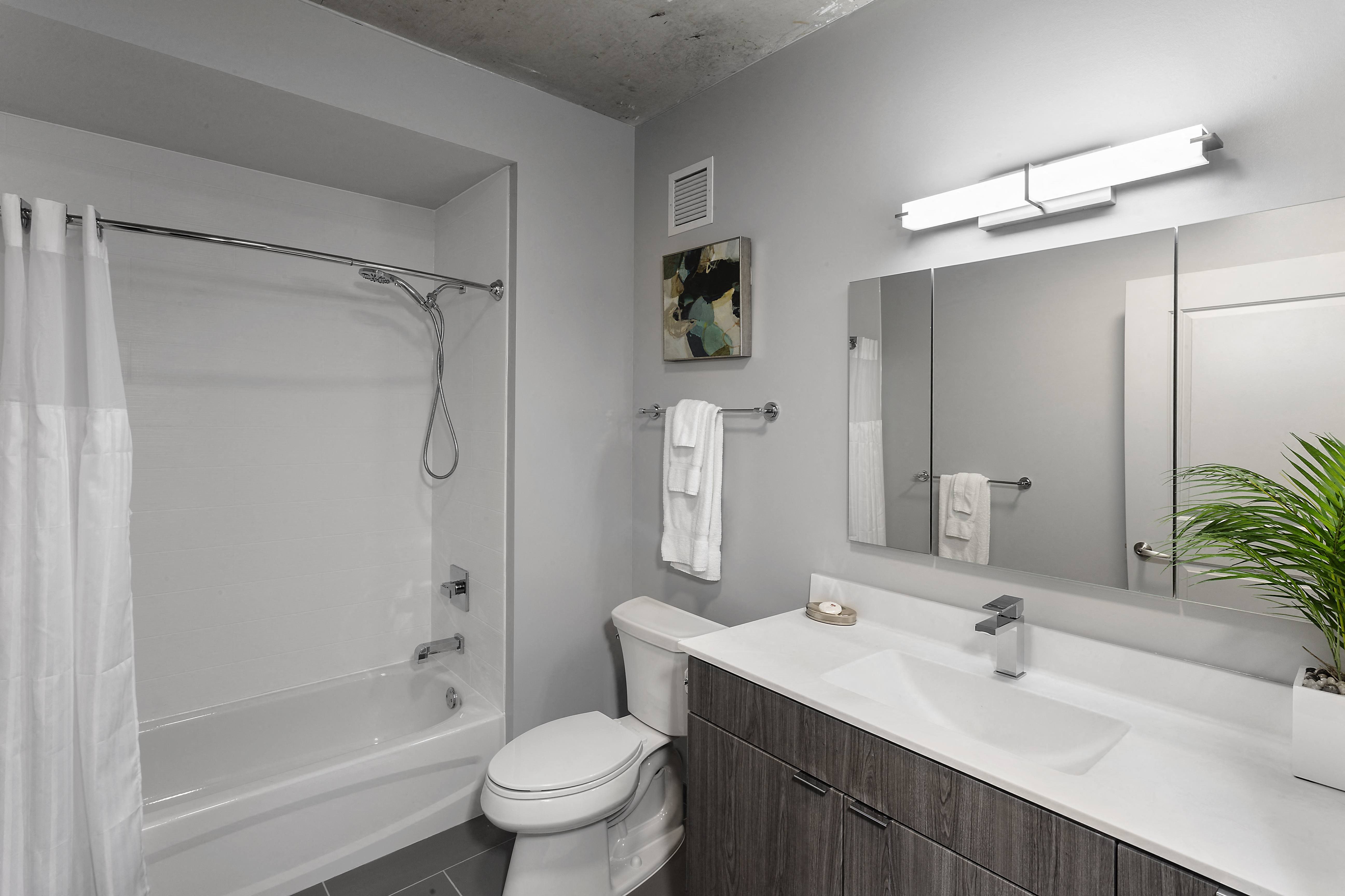 a bathroom with a shower toilet and sink and a mirror at Residences at Addison Clark Apartments, Chicago, IL, 60613
