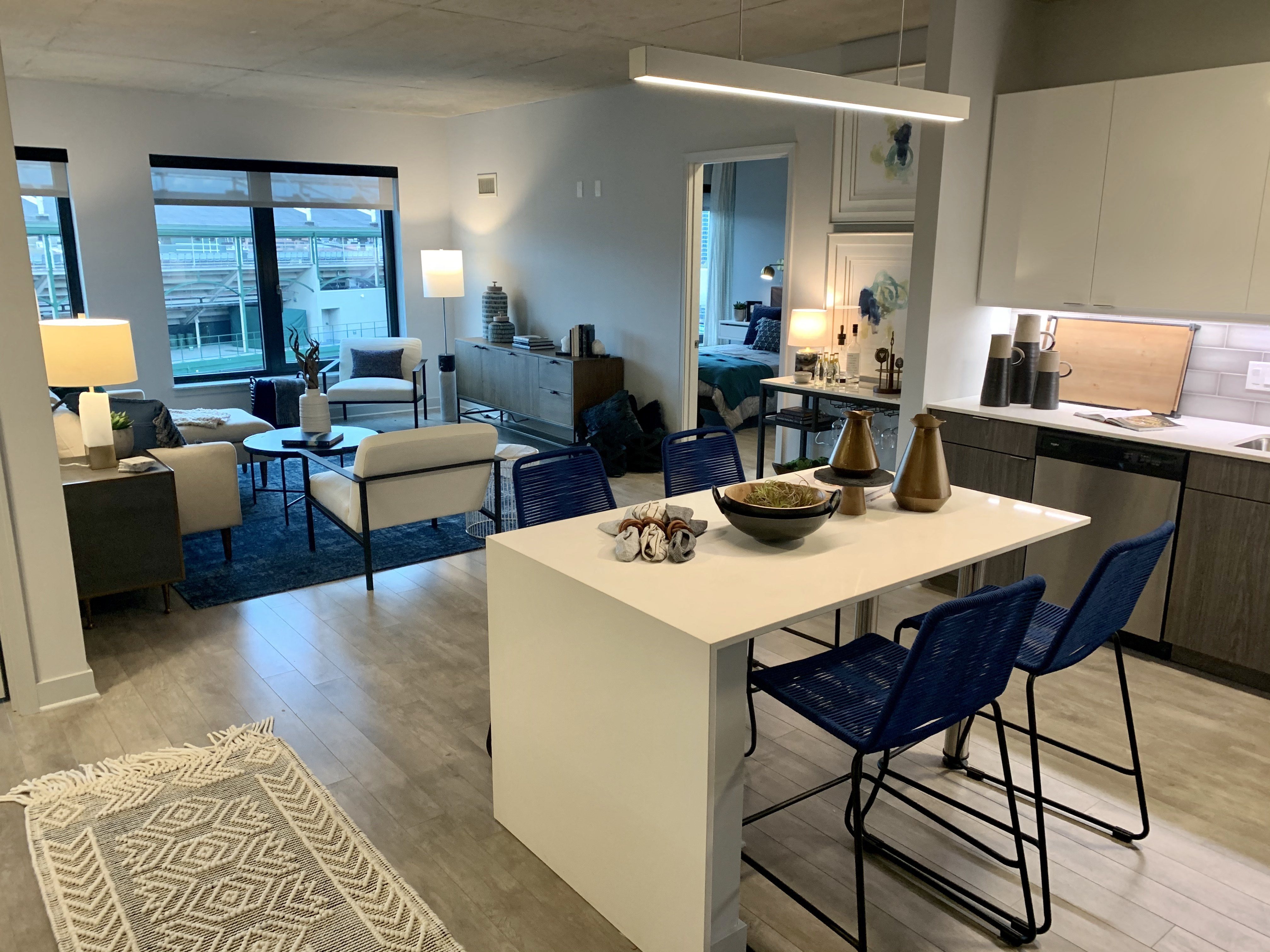 a kitchen and living room with a white island and blue chairs  at Residences at Addison Clark Apartments, Chicago