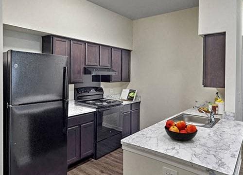 a kitchen with black appliances and a bowl of fruit