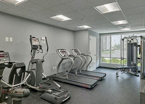 a gym with cardio equipment and a large window