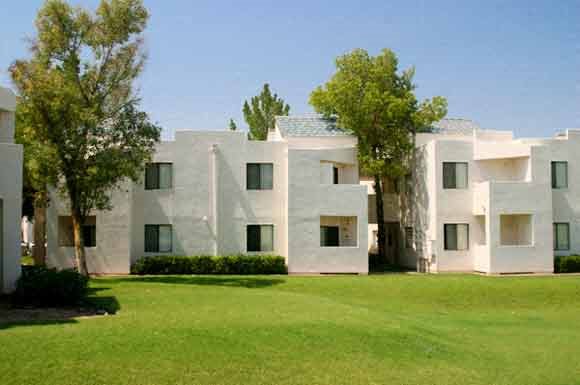 an image of a white apartment building with trees in the background